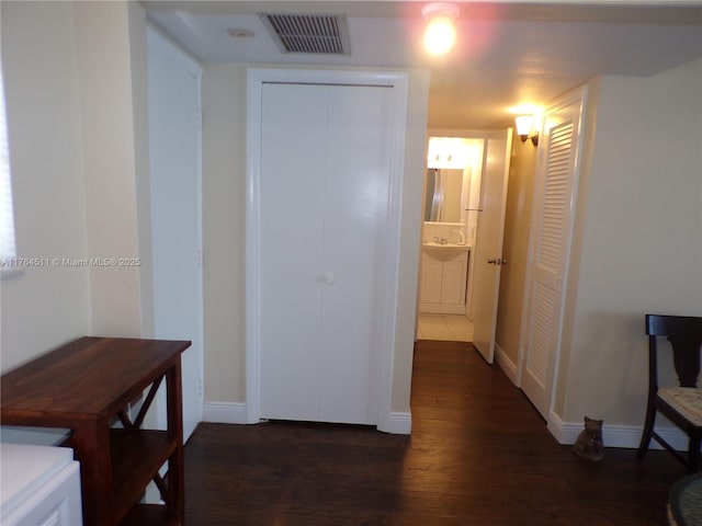 hall featuring dark wood finished floors, visible vents, and baseboards