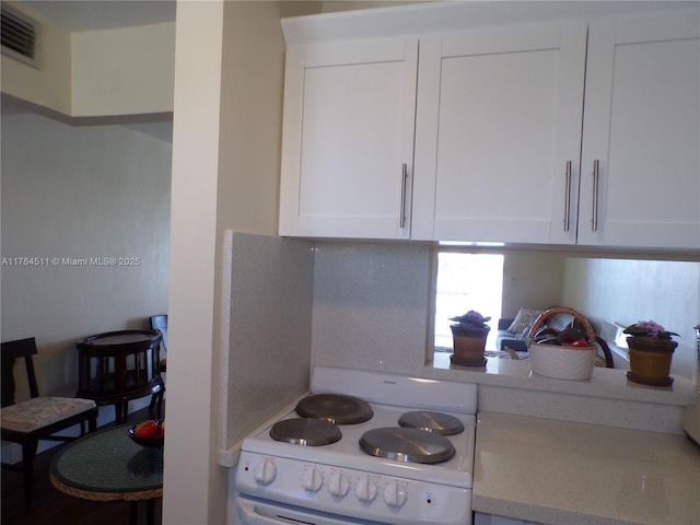 kitchen featuring visible vents, white electric range, white cabinets, light countertops, and decorative backsplash