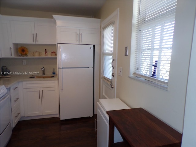 kitchen featuring dark wood finished floors, white cabinets, white appliances, and a sink