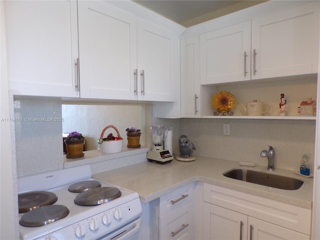 kitchen with a sink, electric range, light countertops, and white cabinetry