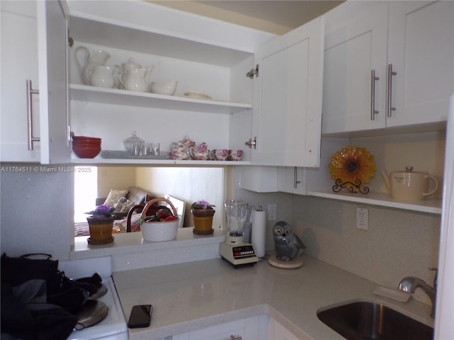 kitchen with a sink, open shelves, light countertops, and white cabinetry