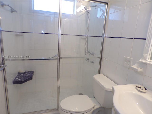 full bathroom with a sink, toilet, tile walls, and a stall shower