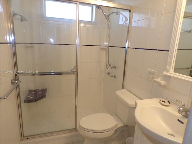 bathroom featuring a shower stall, tile walls, toilet, and a sink