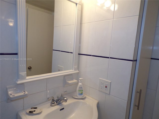 bathroom featuring backsplash, tile walls, and a sink