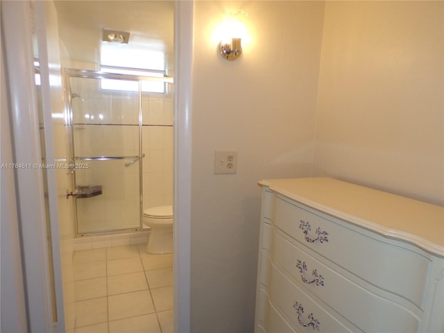 bathroom featuring a shower stall, toilet, and tile patterned floors