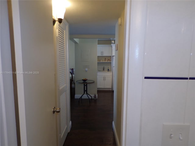 hall with dark wood finished floors and a sink