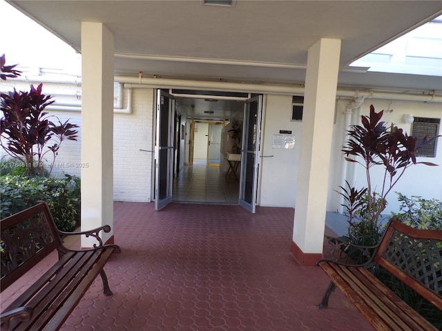 view of exterior entry featuring a patio and brick siding