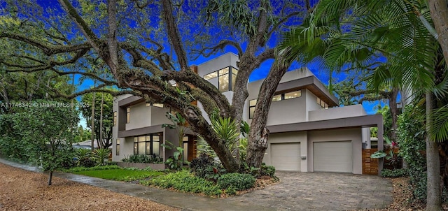 modern home featuring stucco siding, decorative driveway, and a garage