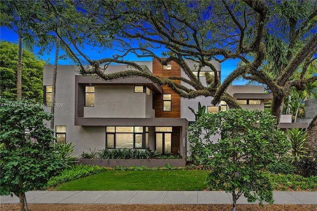 contemporary house with stucco siding and a front lawn