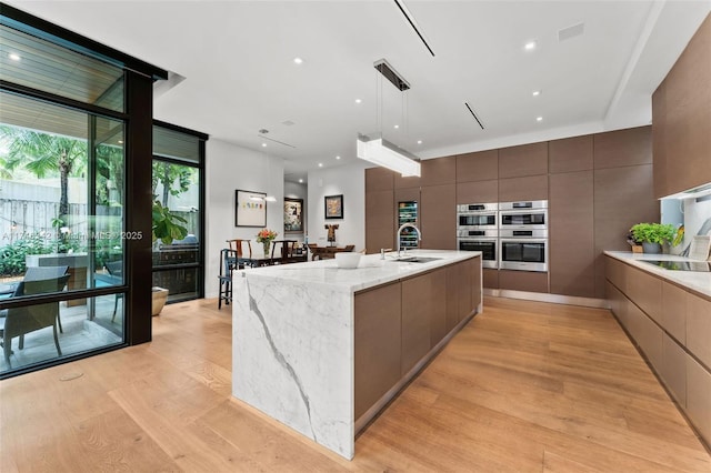 2803 Crystal Ct, Coconut Grove, FL 33133 - kitchen featuring modern cabinets, light wood-type flooring, light stone counters, and a wall of windows
