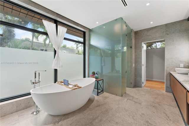 bathroom with visible vents, recessed lighting, a stall shower, a freestanding tub, and vanity