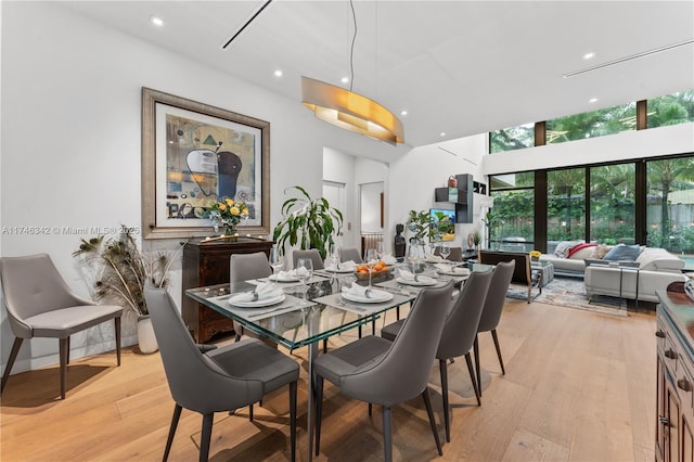 dining area with recessed lighting, a towering ceiling, and light wood finished floors