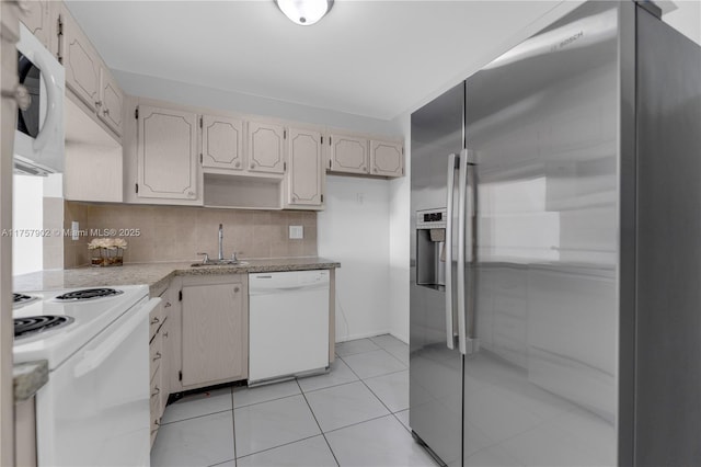 kitchen with a sink, tasteful backsplash, white appliances, light countertops, and light tile patterned floors