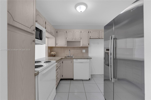 kitchen featuring tasteful backsplash, light tile patterned floors, white appliances, and a sink