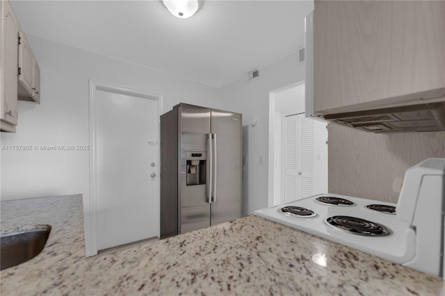 kitchen with visible vents, range with electric cooktop, stainless steel refrigerator with ice dispenser, ventilation hood, and light stone countertops