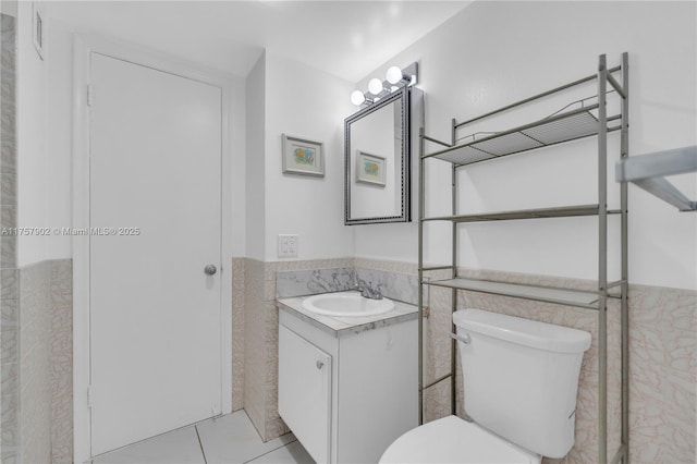 bathroom with vanity, tile walls, wainscoting, and toilet