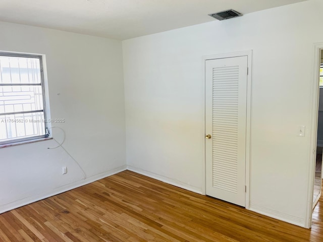 unfurnished room featuring visible vents, light wood-type flooring, and baseboards