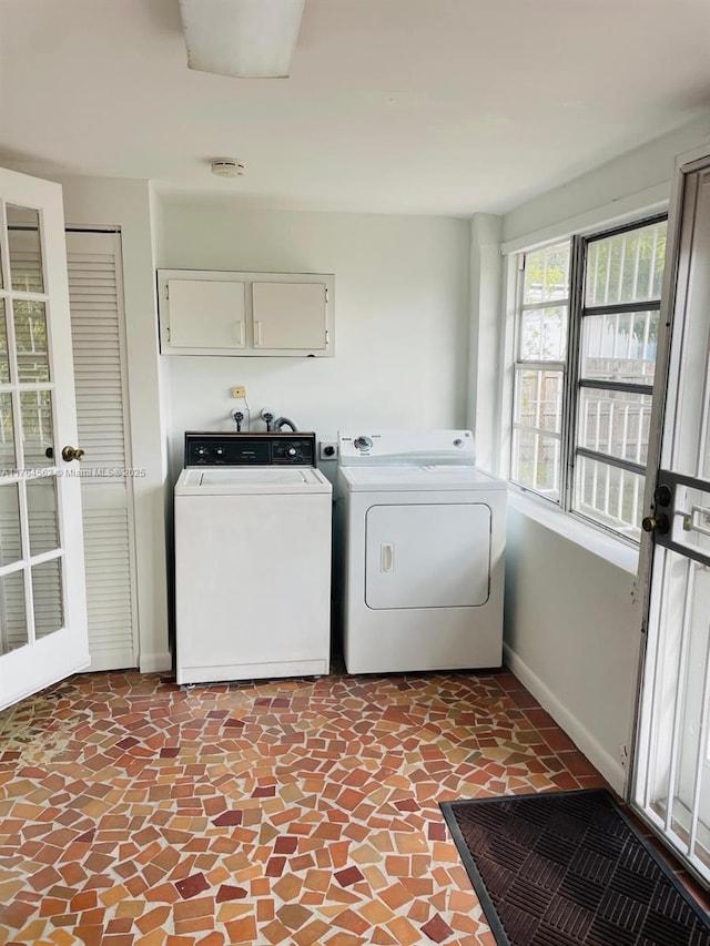 washroom featuring washing machine and clothes dryer, cabinet space, and baseboards