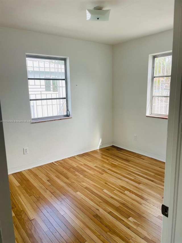 spare room with baseboards and light wood-style floors