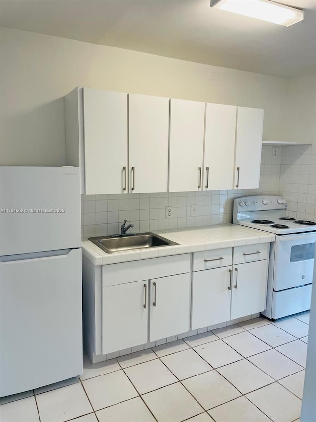 kitchen with white appliances, white cabinets, backsplash, and a sink