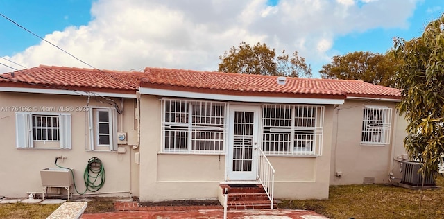 view of front facade featuring stucco siding, central AC unit, and a tiled roof