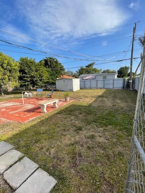 view of yard with a shed, an outdoor structure, and fence