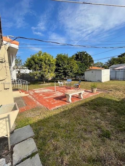 view of yard featuring a storage shed, fence, and an outdoor structure