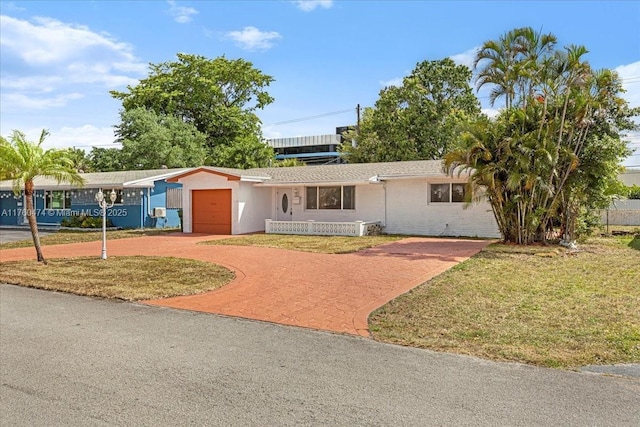 ranch-style house with decorative driveway, a front yard, and an attached garage