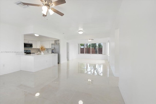 unfurnished living room with visible vents, baseboards, and ceiling fan