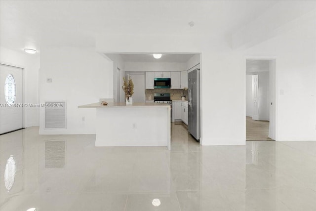 kitchen with backsplash, stainless steel appliances, a peninsula, white cabinets, and light countertops