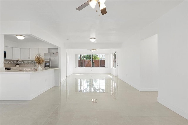 unfurnished living room with baseboards and a ceiling fan