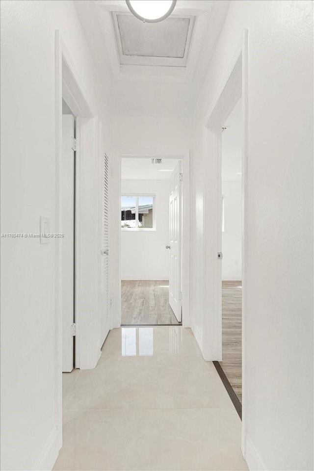 corridor featuring attic access and baseboards