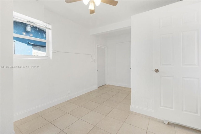 unfurnished room featuring light tile patterned floors, a ceiling fan, and baseboards