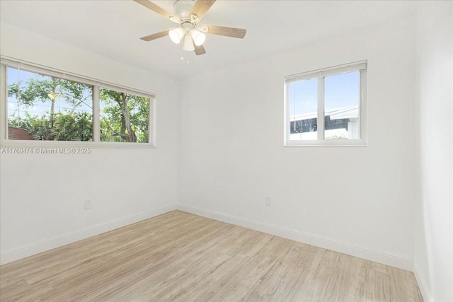 spare room featuring a wealth of natural light, baseboards, light wood-style floors, and ceiling fan