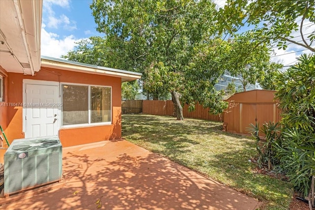 view of yard with fence, a shed, central AC unit, an outdoor structure, and a patio