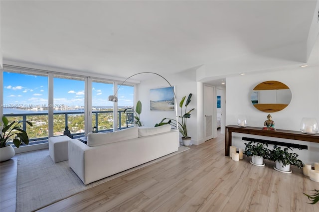 living room with floor to ceiling windows, baseboards, light wood-style floors, and a water view