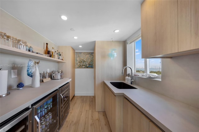 kitchen featuring beverage cooler, modern cabinets, light countertops, and a sink