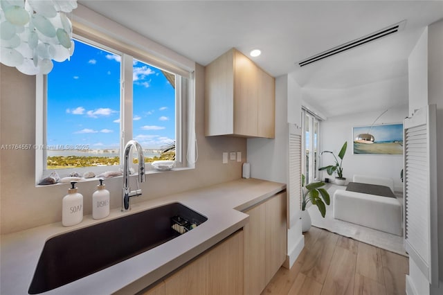 kitchen featuring light brown cabinetry, modern cabinets, light countertops, and a sink