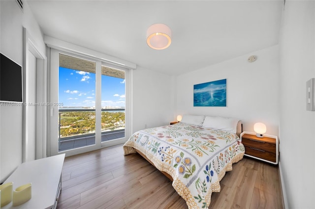 bedroom with access to outside, a wall of windows, and wood finished floors