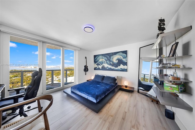 bedroom with floor to ceiling windows, multiple windows, and wood finished floors