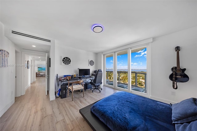 bedroom featuring access to exterior, light wood-style flooring, a wall of windows, and baseboards