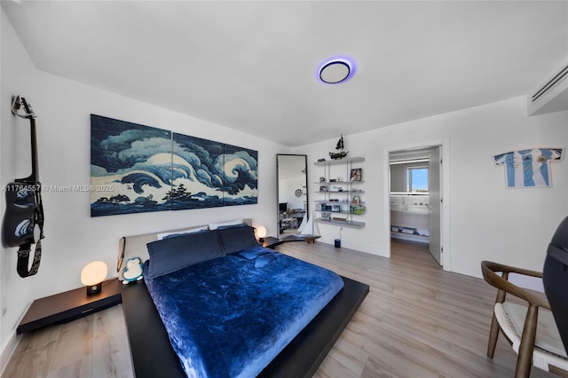 bedroom featuring ensuite bath, baseboards, and wood finished floors