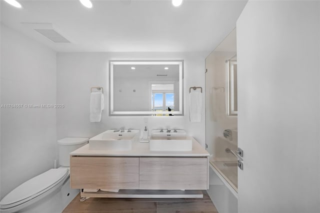 full bathroom with double vanity, shower / bath combination, toilet, and a sink