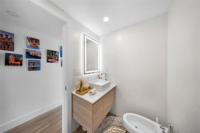 half bathroom featuring vanity, wood finished floors, a bidet, and baseboards