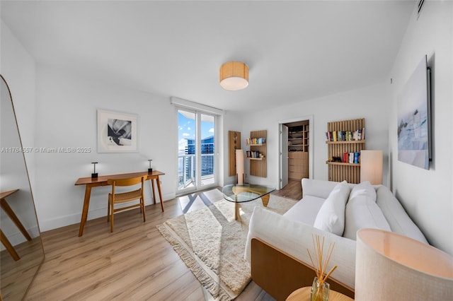 living room featuring visible vents, baseboards, floor to ceiling windows, and light wood finished floors