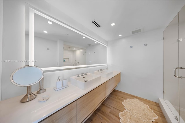 full bathroom featuring a shower stall, wood finished floors, visible vents, and a sink