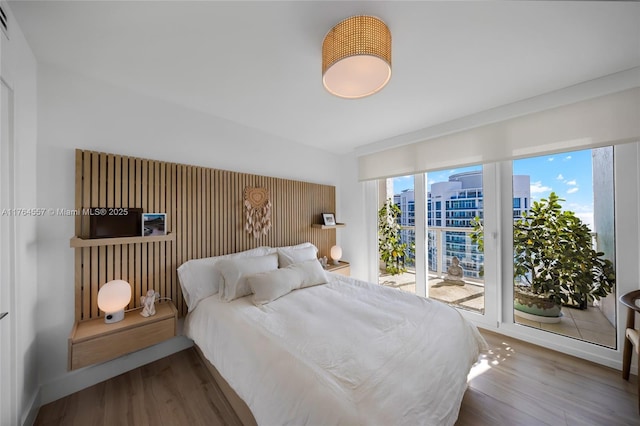 bedroom featuring wood finished floors, baseboards, multiple windows, and access to exterior