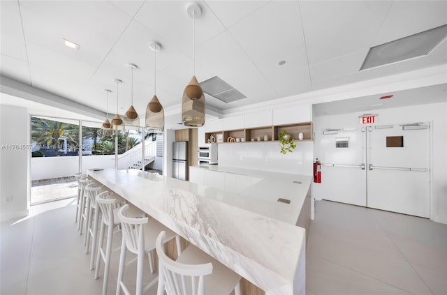 kitchen featuring light tile patterned floors, open shelves, freestanding refrigerator, hanging light fixtures, and white cabinets