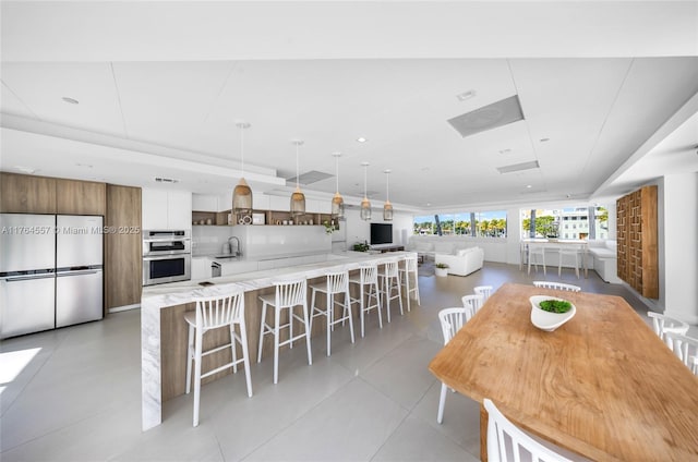 kitchen featuring pendant lighting, a sink, a kitchen breakfast bar, stainless steel appliances, and light countertops