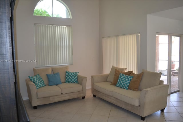 living area with light tile patterned floors, baseboards, and a high ceiling